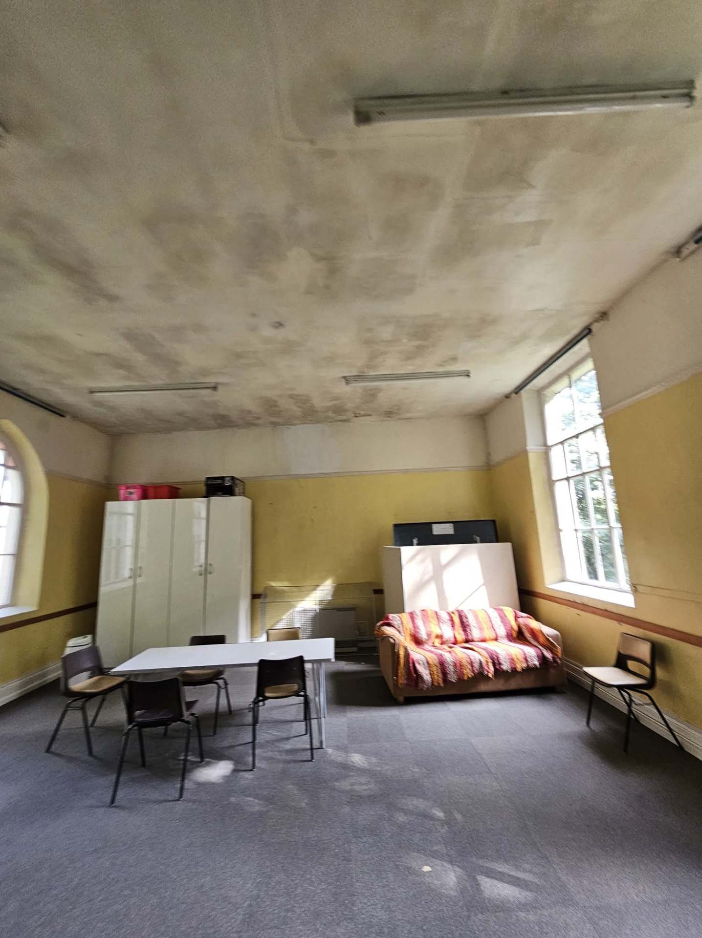 Congleton community hall side room with damp-marked ceiling and yellow walls before redecoration