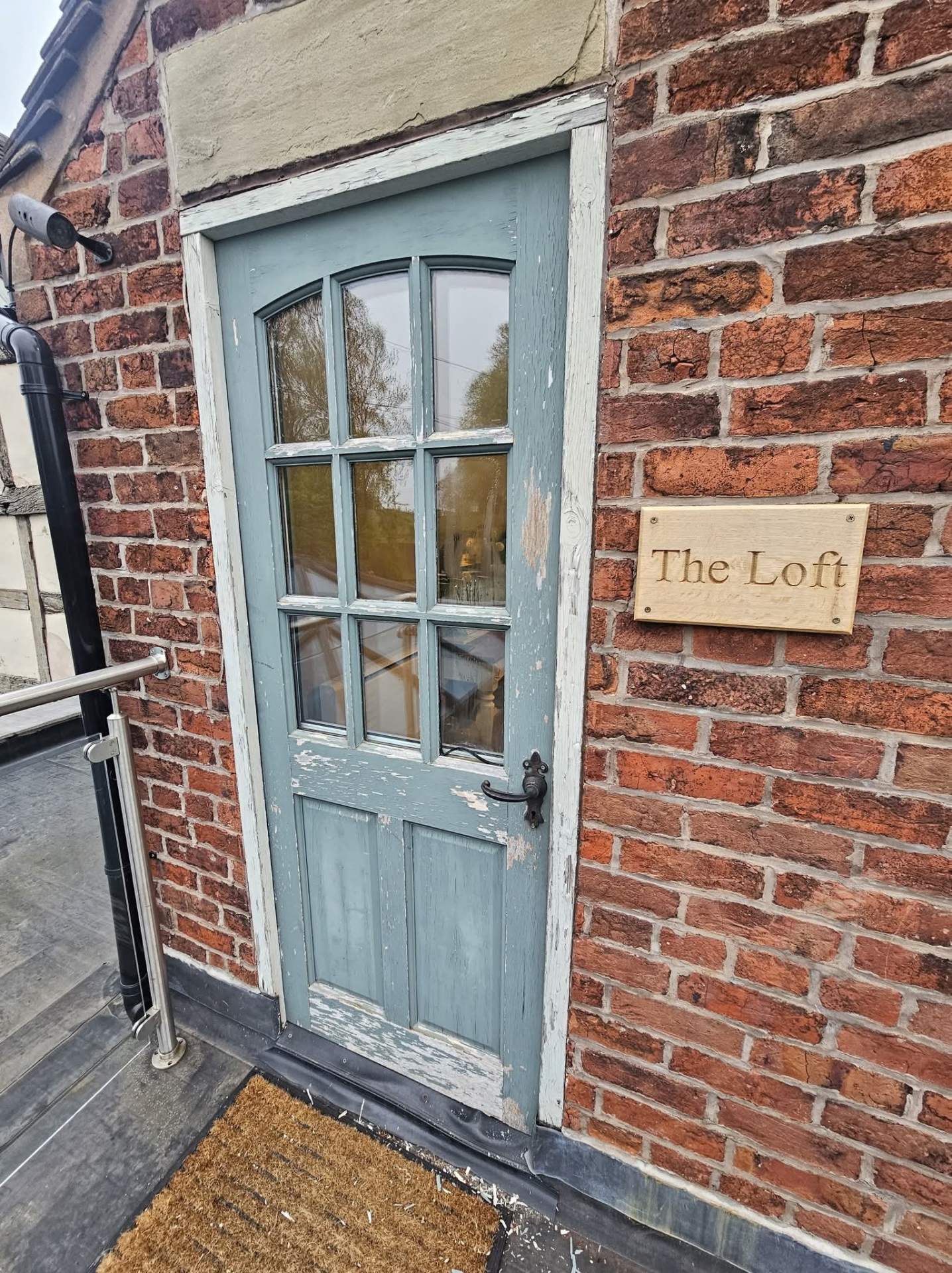 Weathered blue timber entrance door in Cheshire with flaking paint before exterior repainting