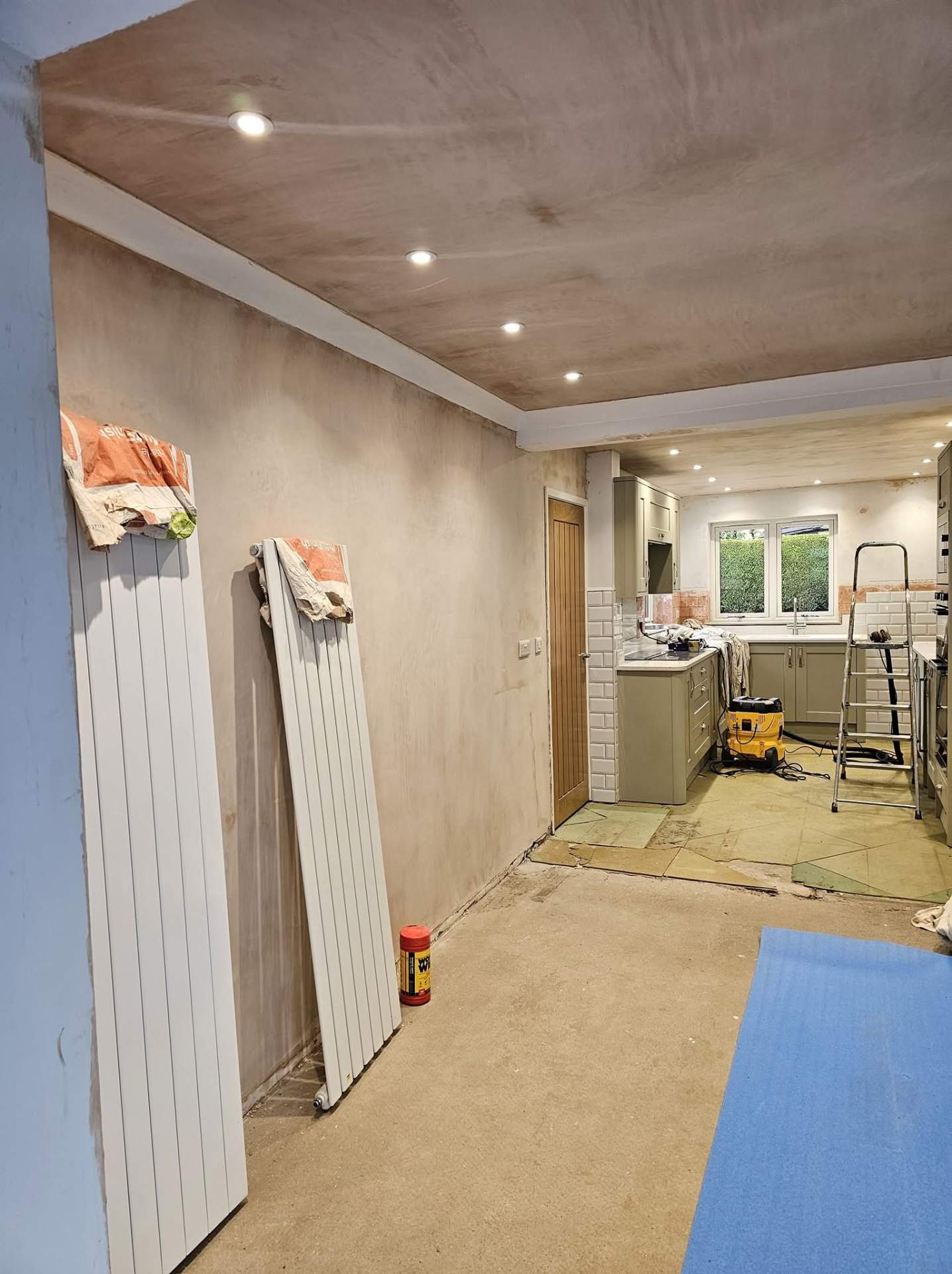 Freshly plastered kitchen and hallway in Cheshire before painting, radiators waiting to be fitted